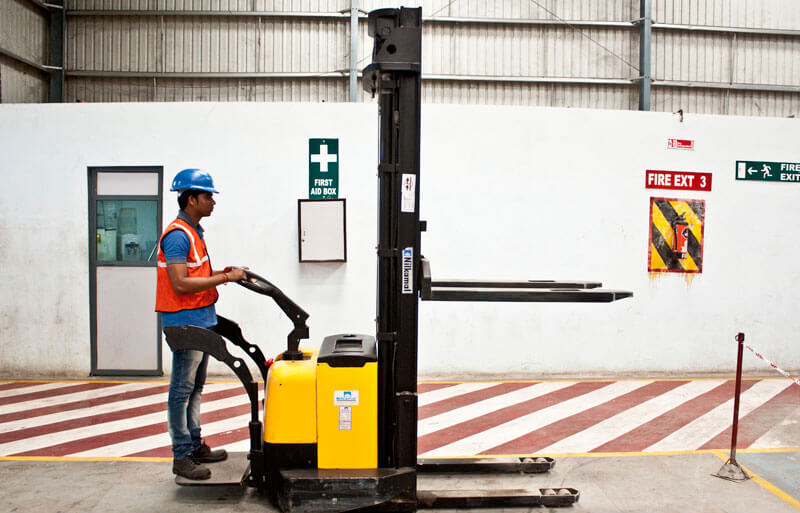 Worker with fork lift in a warehouse