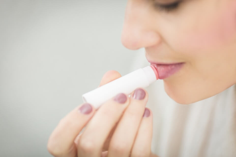 Model applying pink lipstick