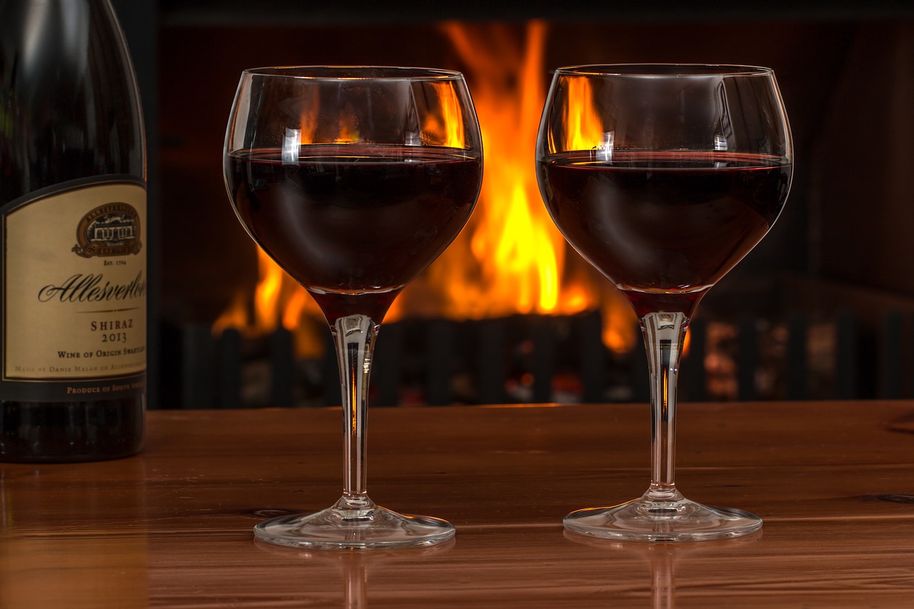 Lifestyle photo of red wine goblets near fireplace