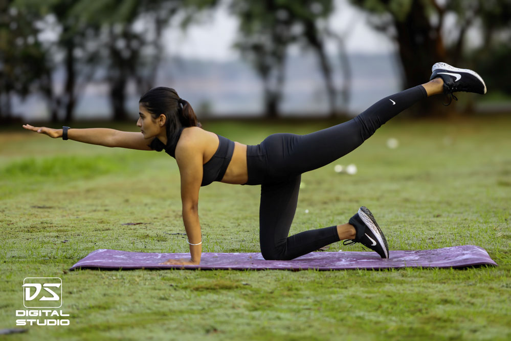 Fitness model posing outdoor on a yoga mat