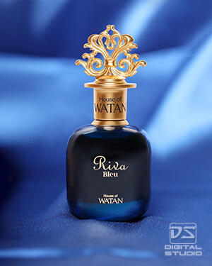 Real styled product photograph of a green glass perfume bottle with fabric background and decorative flower petals.