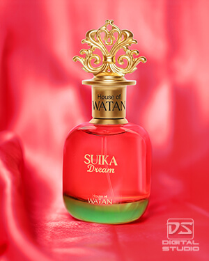 Real luxury perfume product photograph featuring a red glass fragrance bottle against a softly styled pink fabric background.